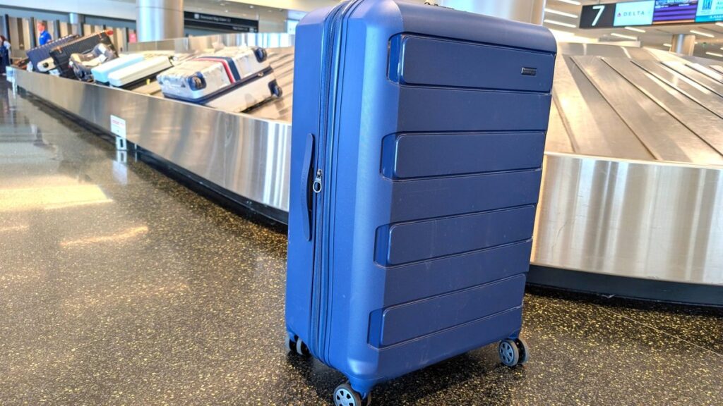 Large checked suitcase at an airport baggage claim — things that are 43 inches long