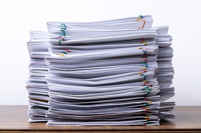 A stack of legal size paper on a desk — three 14 inch legal sheets laid end to end are things that are 42 inches long